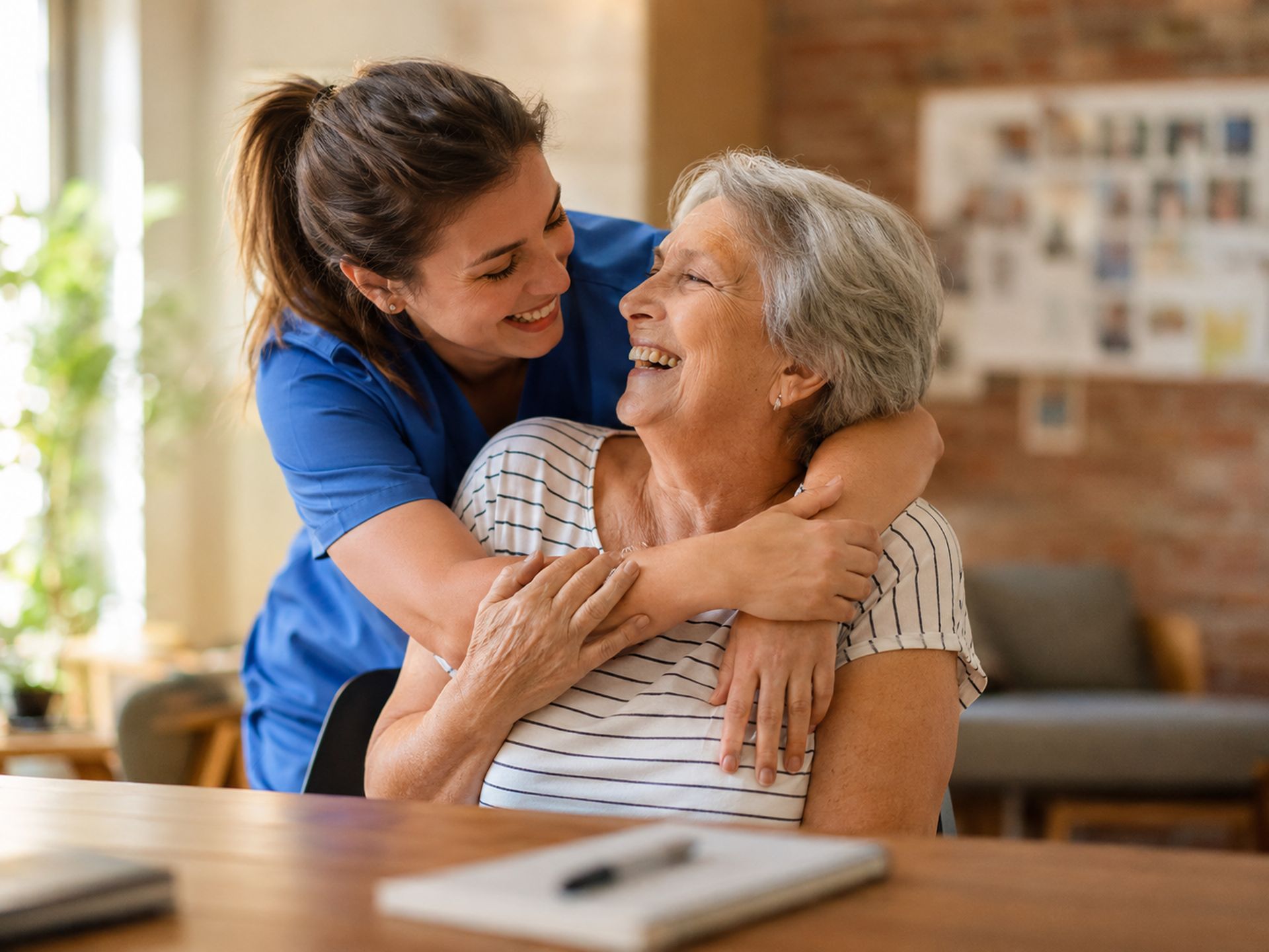 A caregiver hugging a smiling older woman at home